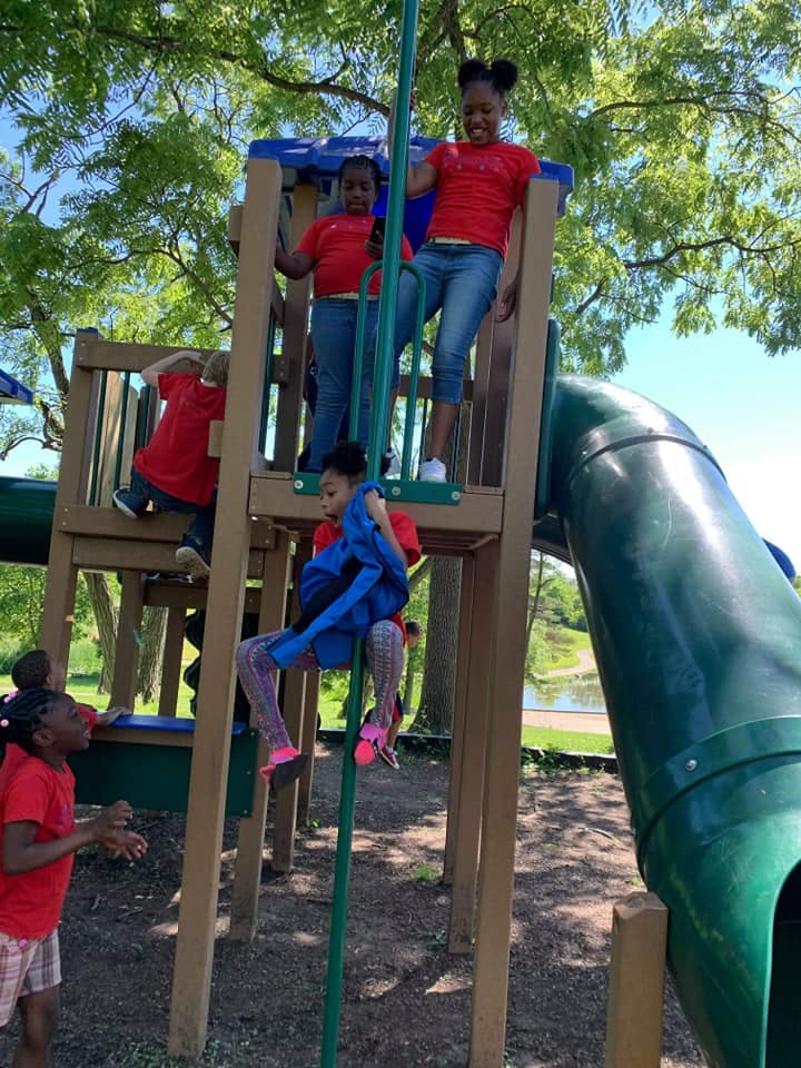 Children playing on a playground structure with a slide and climbing structure