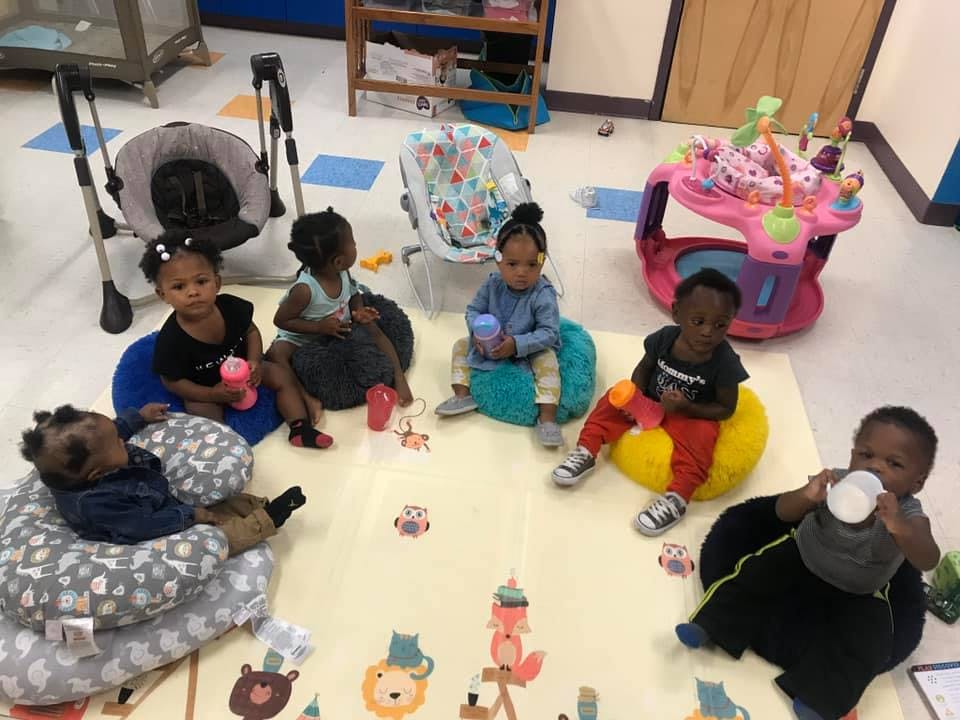 Multiple children sitting on a playmat with toys