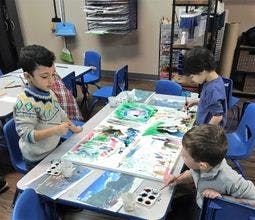 Three children at a table with art supplies