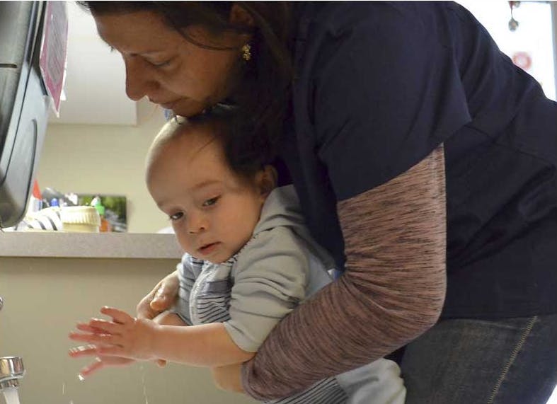 Person helping a child wash hands at a sink