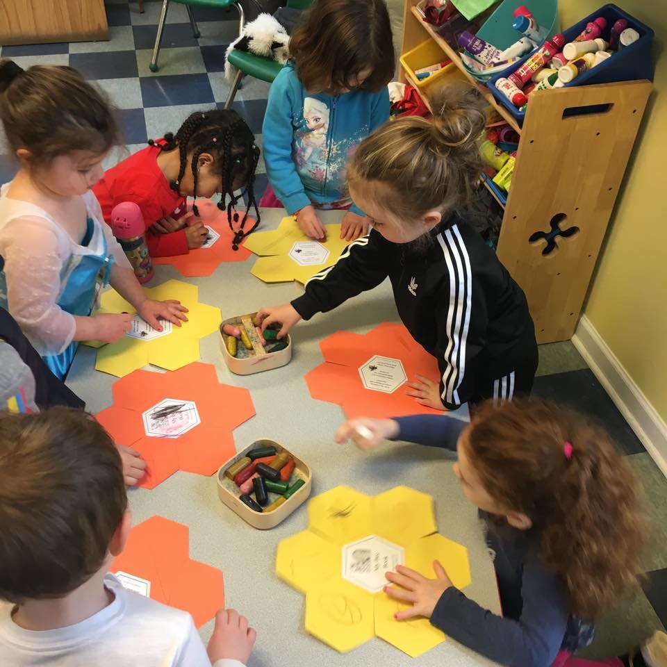 Children coloring on large paper shapes on the floor