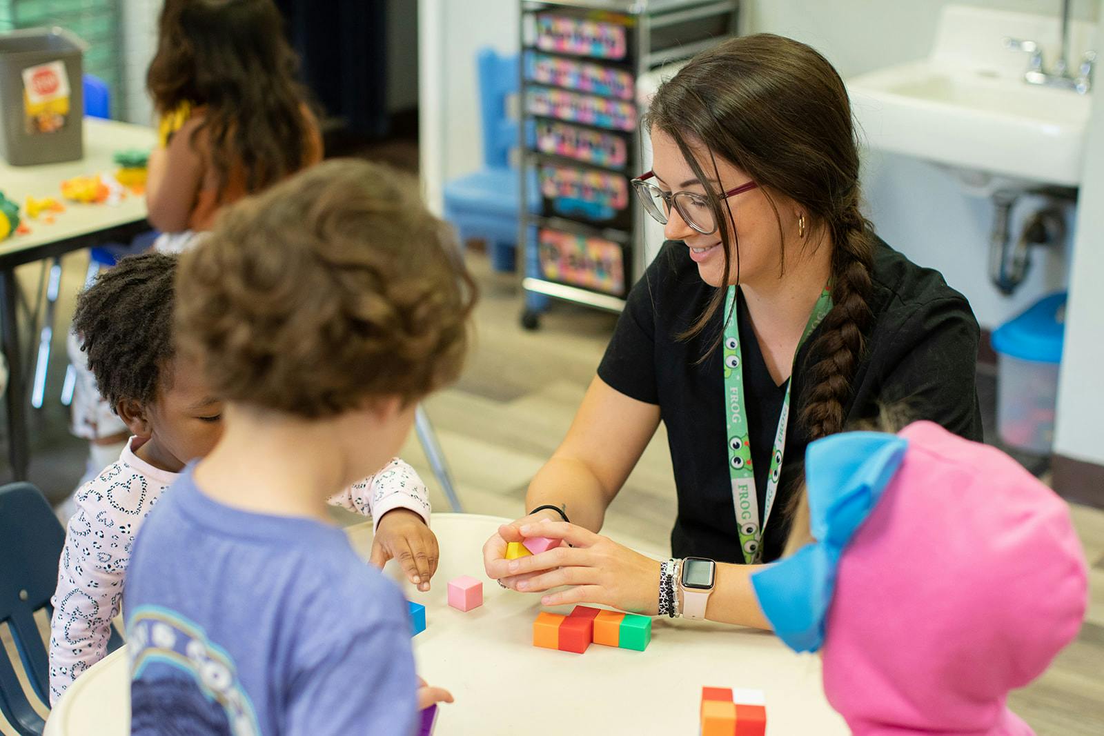 Adult and children playing with colorful blocks at a table