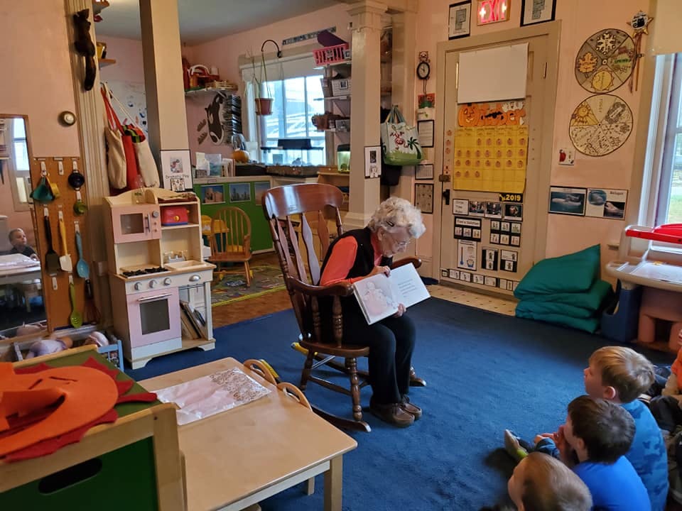 Person reading a book to children in a classroom