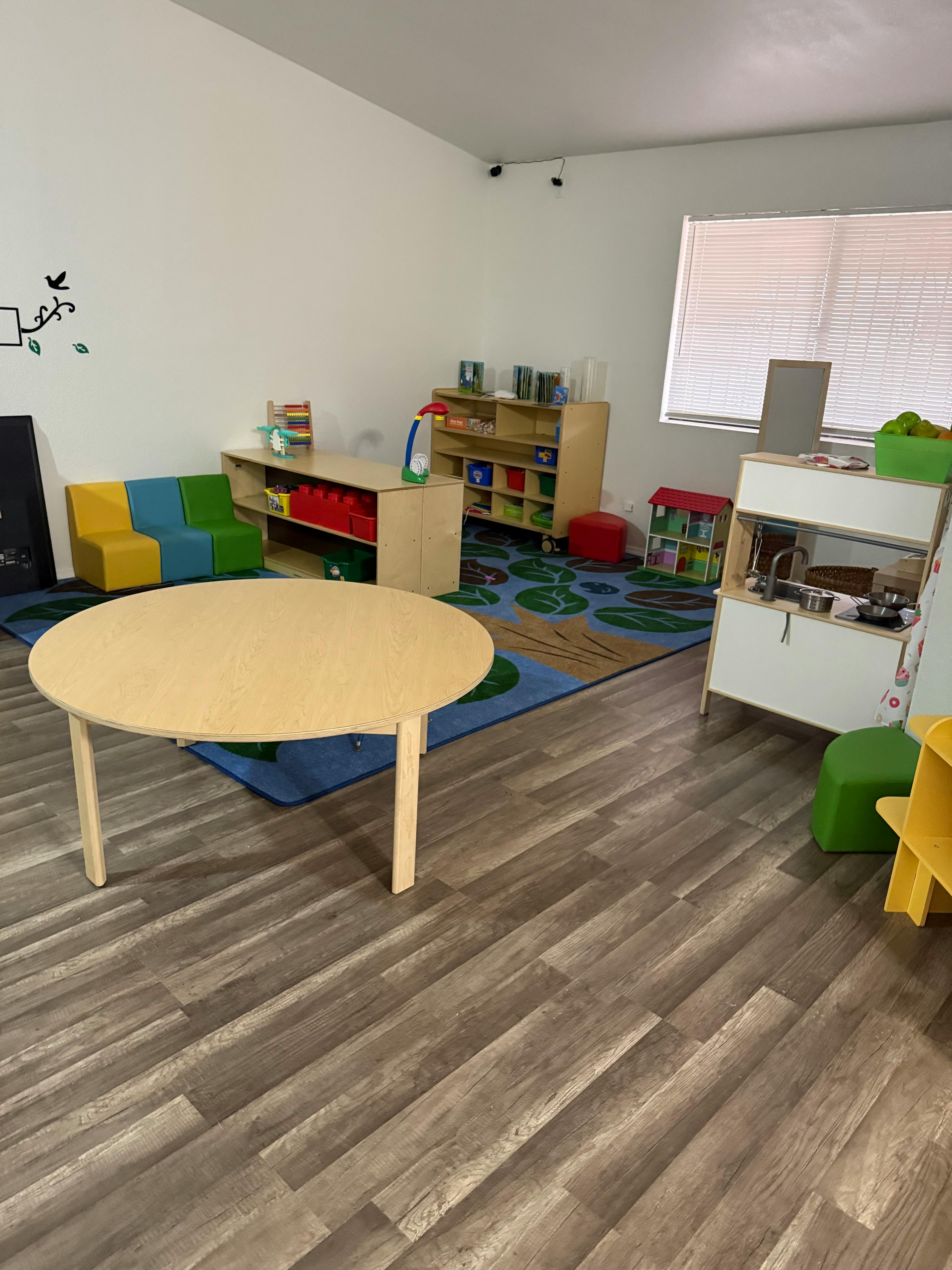 Classroom with a round table, colorful seating, and toy shelves