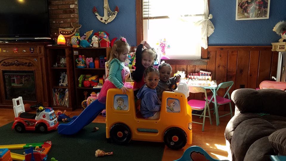 Children playing with a toy bus and slide indoors