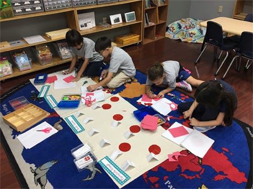 Children working on a craft project on a rug in a classroom