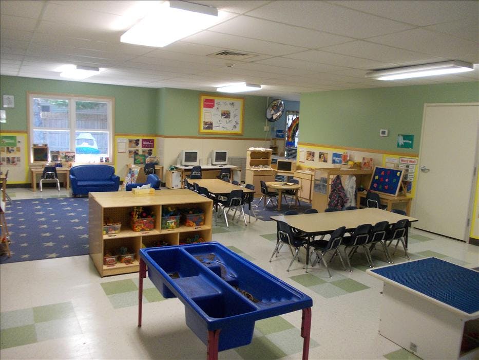 An empty classroom with multiple tables, chairs, and play areas