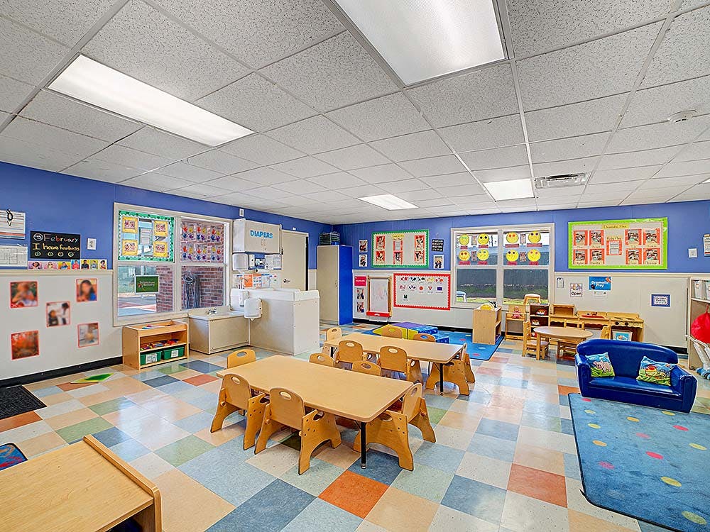 Classroom with small tables and chairs, blue walls, and a changing station
