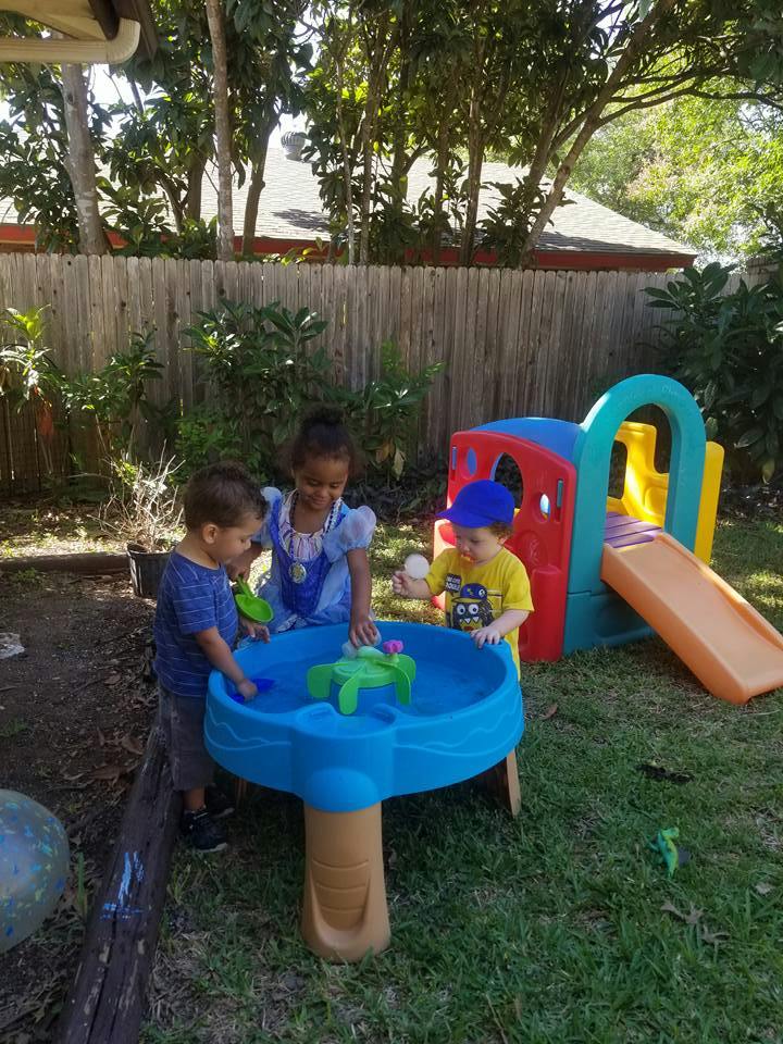 Three children playing with a water table outdoors