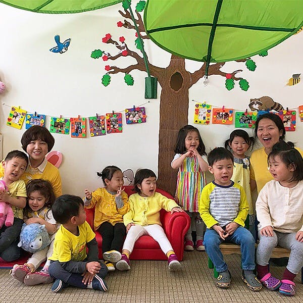 Two adults with a group of children in a classroom