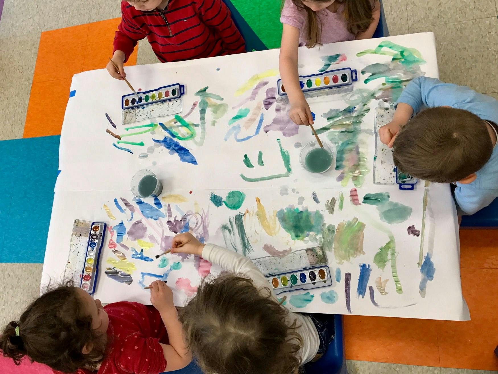 Children painting on a large sheet of paper