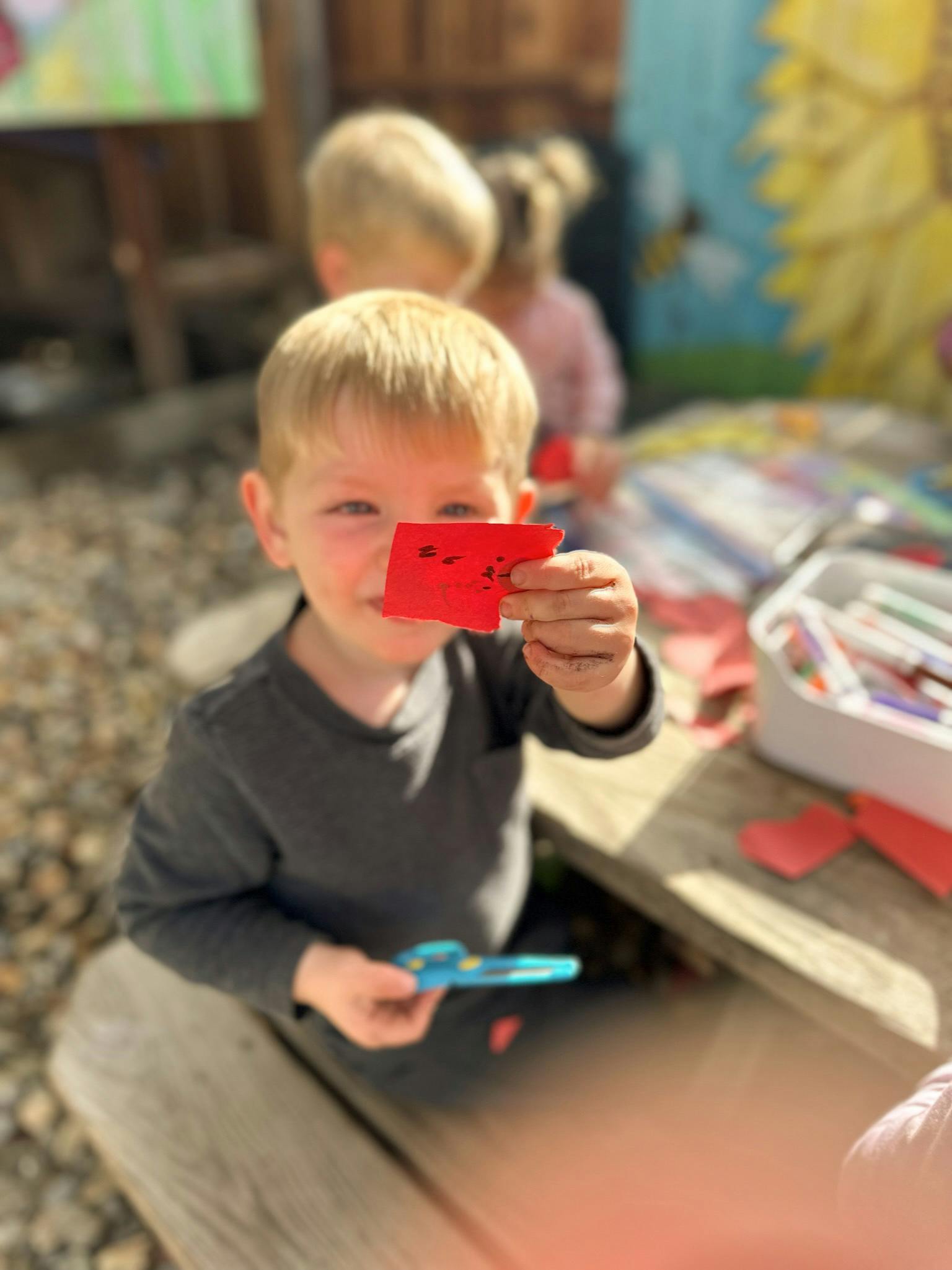 Child holding up a small red paper cutout