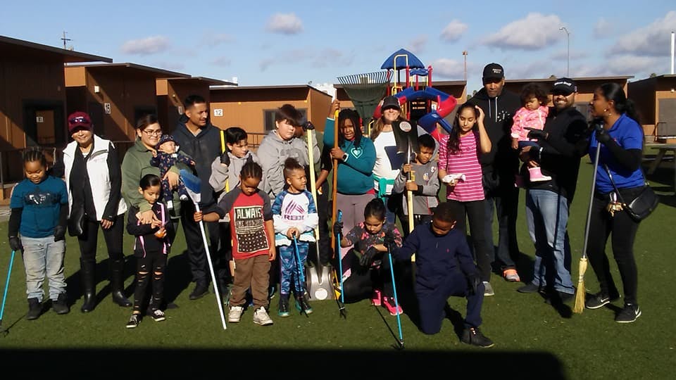 Group of people and children holding sticks on a grassy area