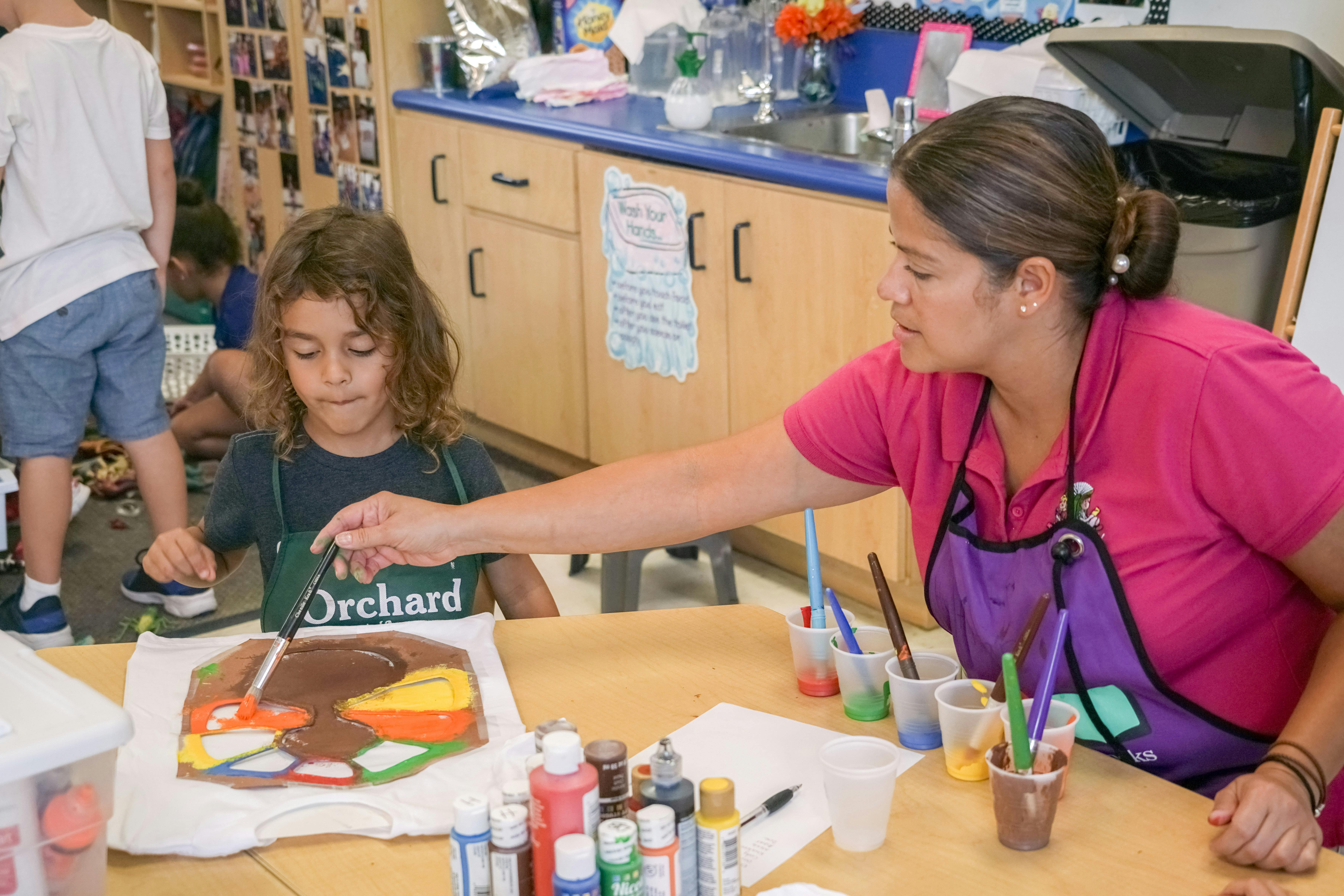 Adult and child painting together in a classroom