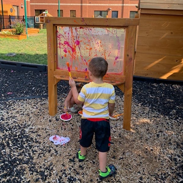 Child painting on a clear easel outdoors