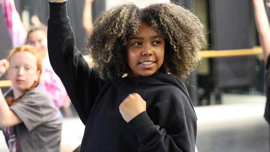 Child with curly hair raising one arm