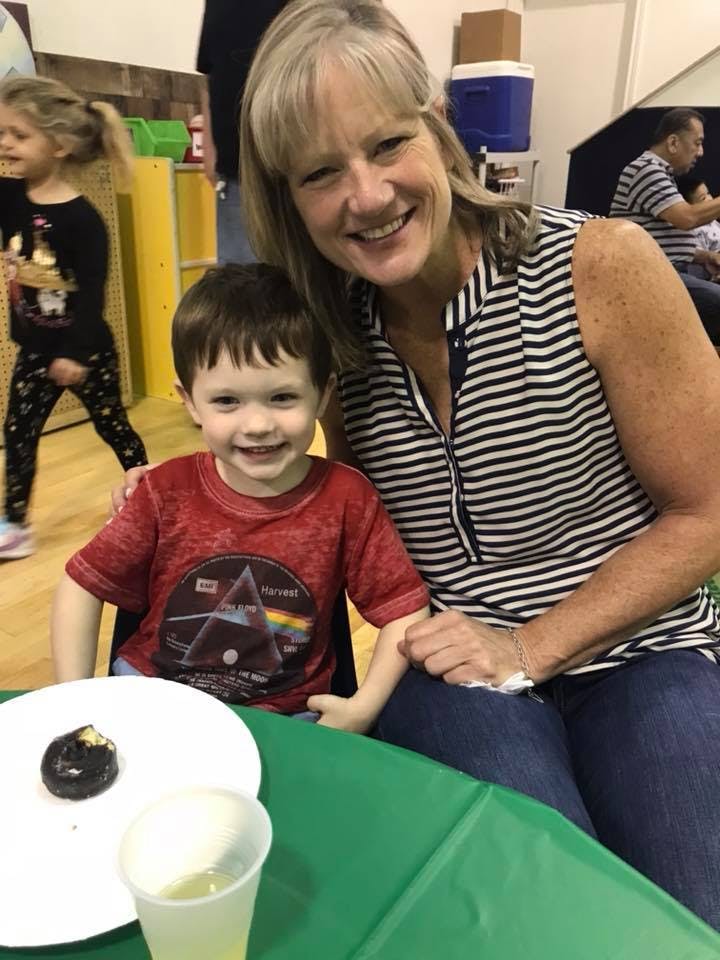 Adult and child smiling at a table with a donut and drink