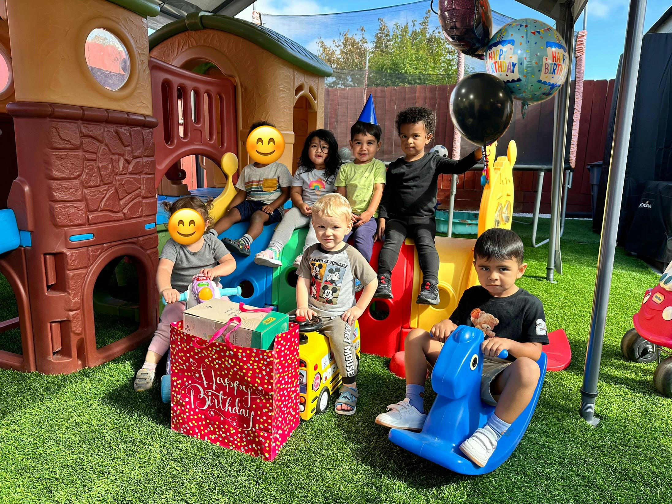 Children playing on outdoor playground equipment with gifts and balloons