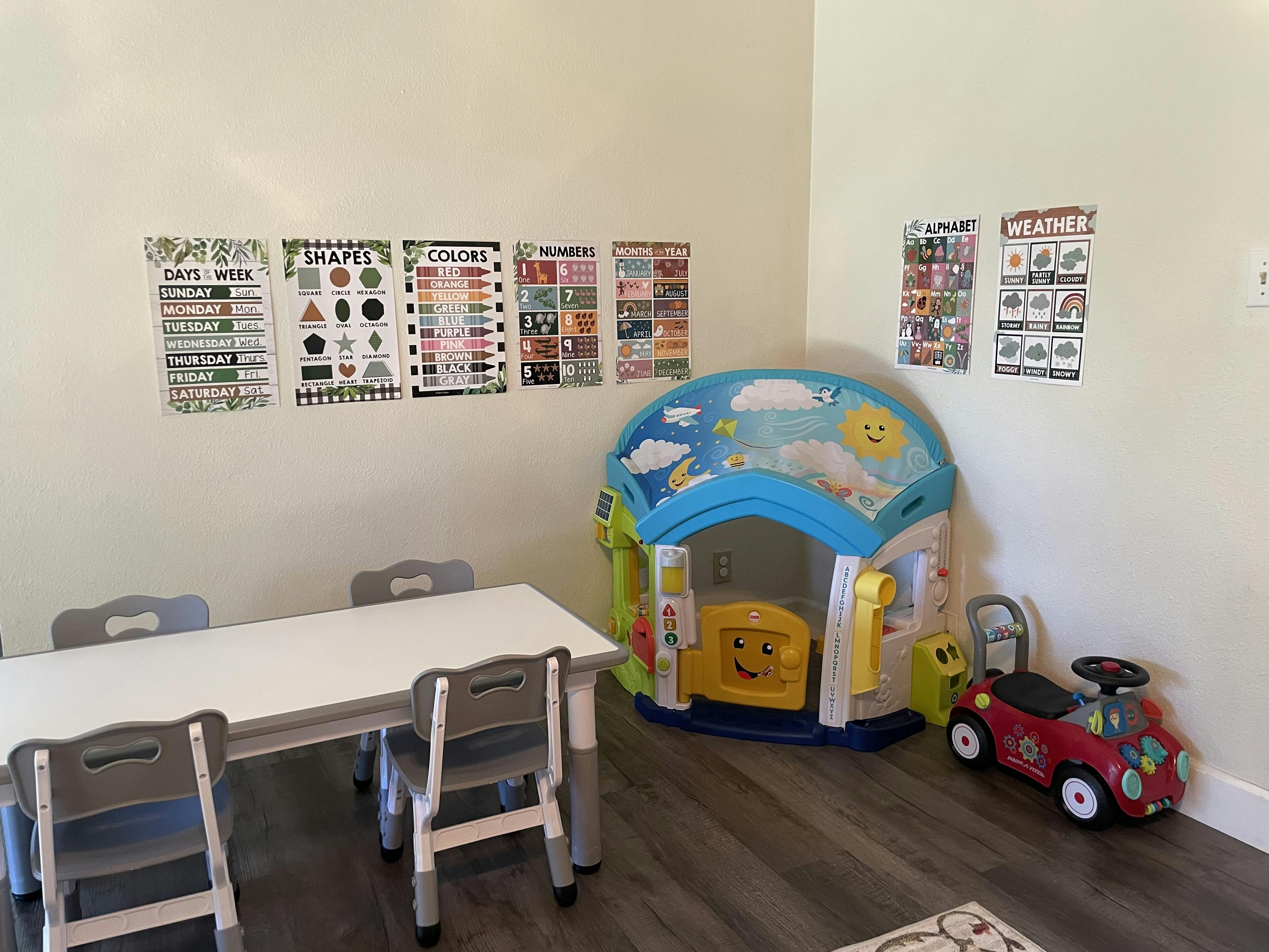 Playroom with educational posters on the wall, a small table, chairs, and toys