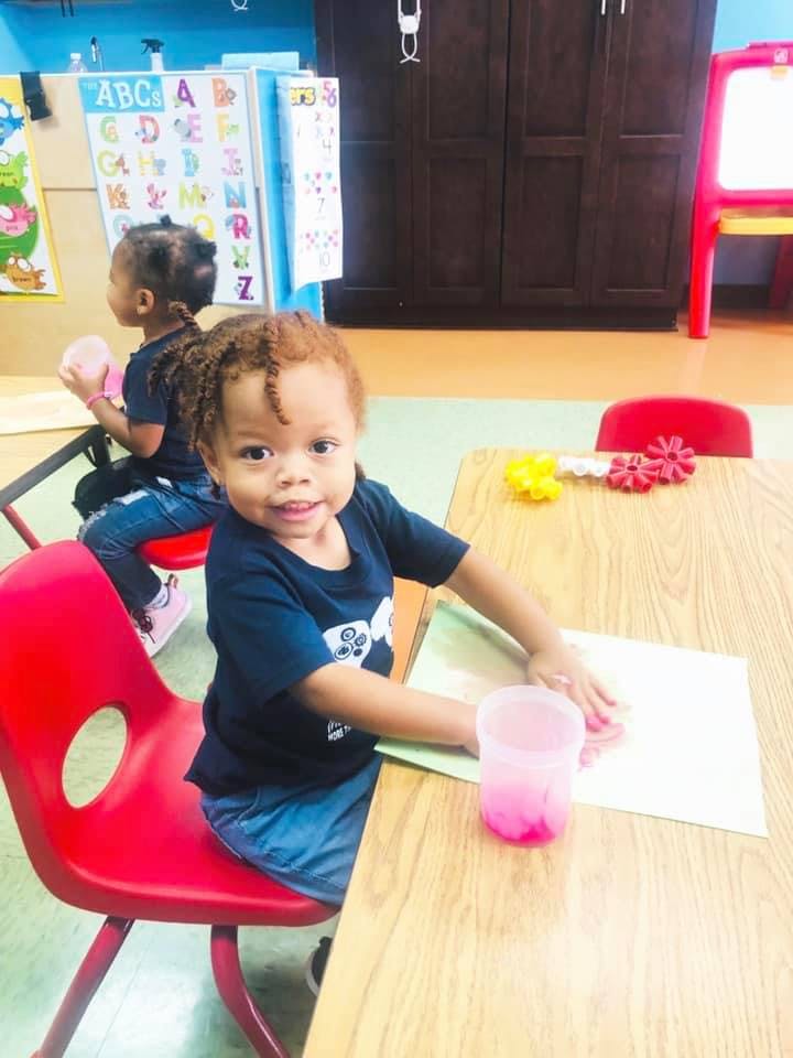 Child sitting at a table with paper and a cup