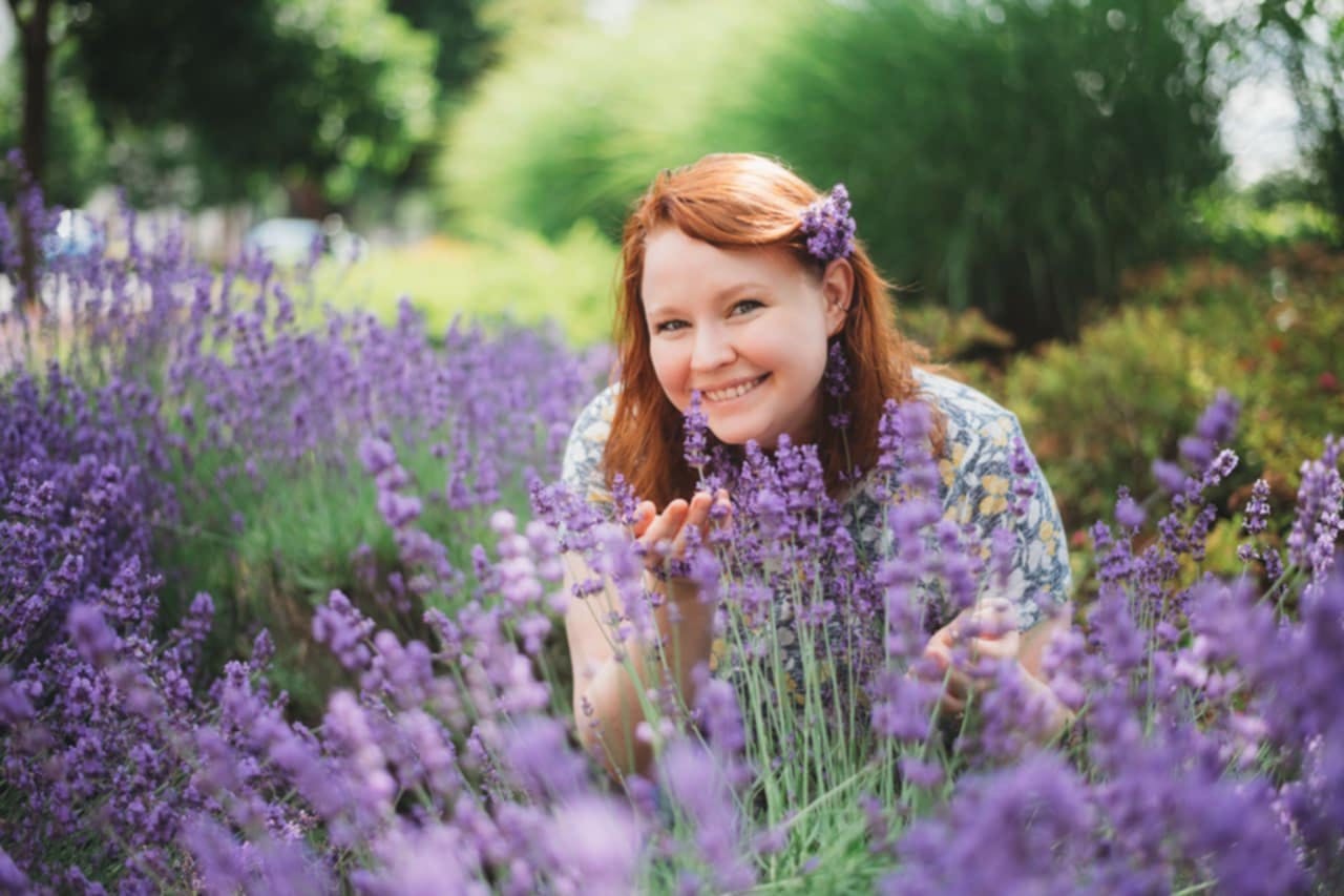 Person with red hair smiling among lavender flowers