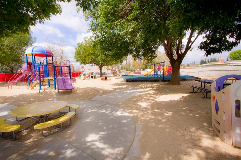 Playground with colorful play structures, picnic tables, and trees