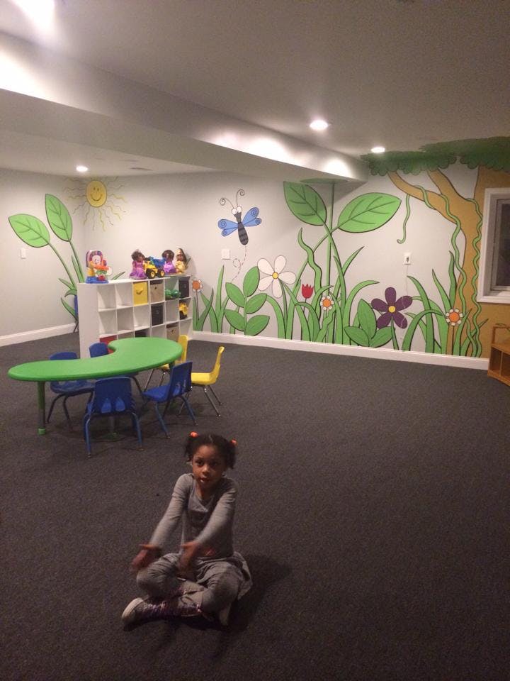 Child sitting on floor in a room with nature-themed wall murals