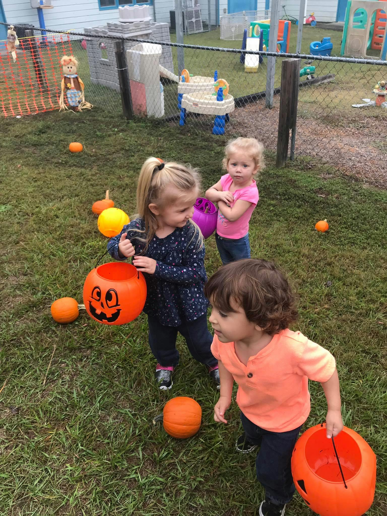 Three children with Halloween pumpkin buckets on grass