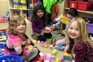 Four children playing with toys on a rug