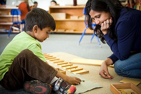 Adult and child on floor playing with wooden blocks