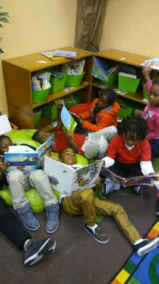 Children sitting on the floor and beanbags reading books in a classroom