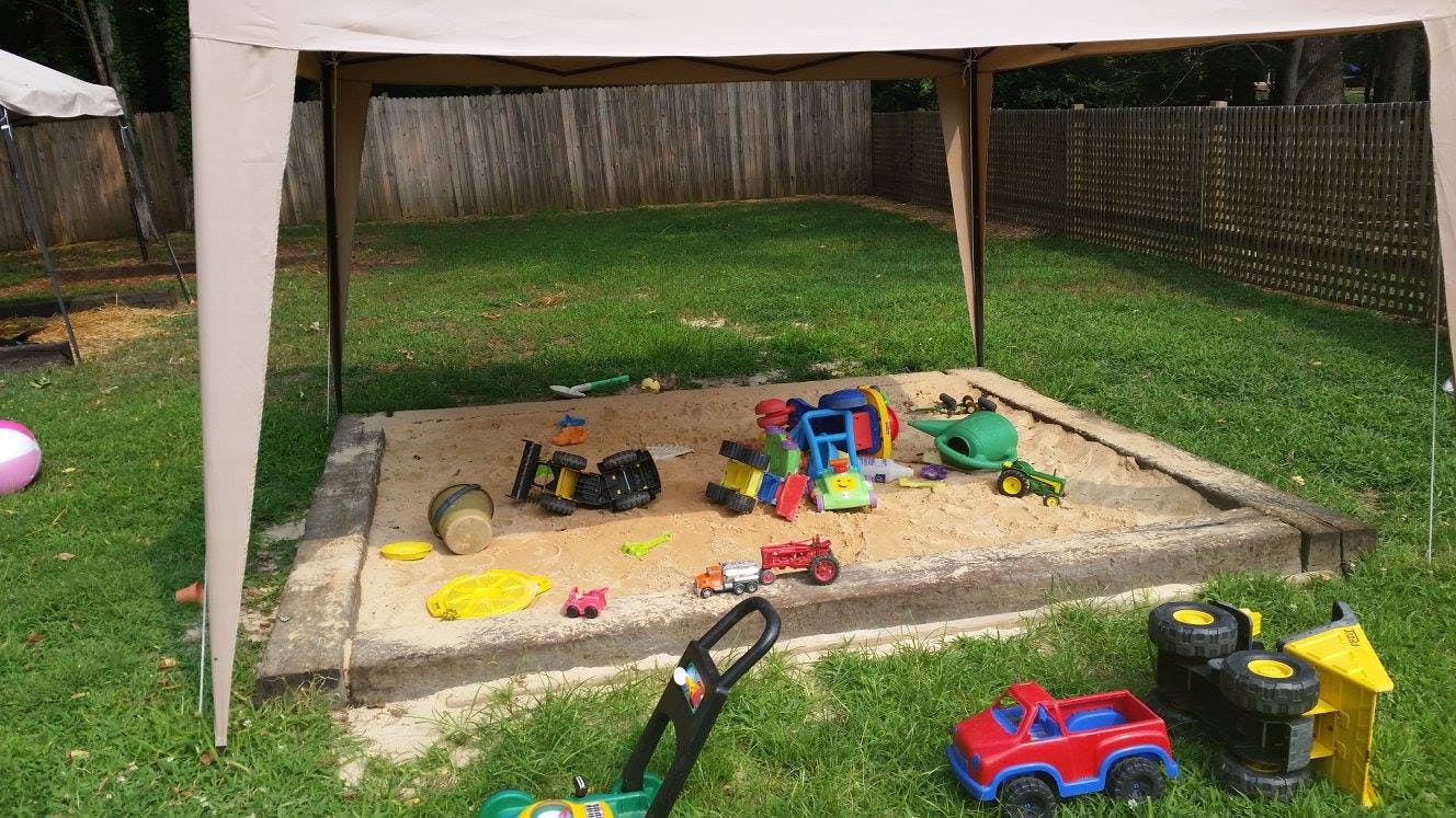 Sandbox with various toys under a canopy