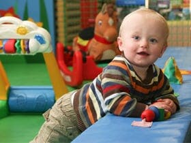 Child on hands and knees on a soft play surface