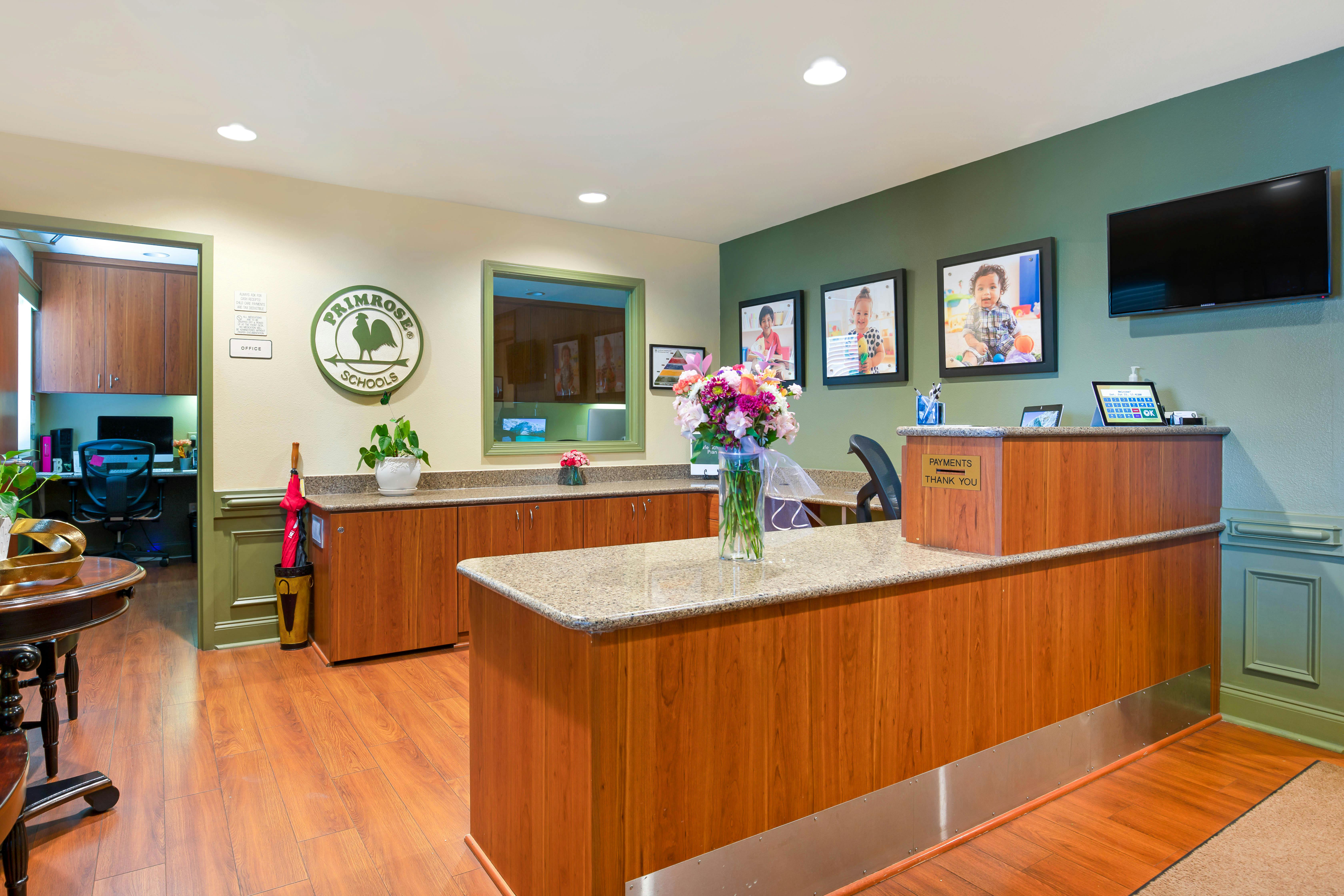 Reception desk with wood and granite finishes, bouquet of flowers, and child portraits