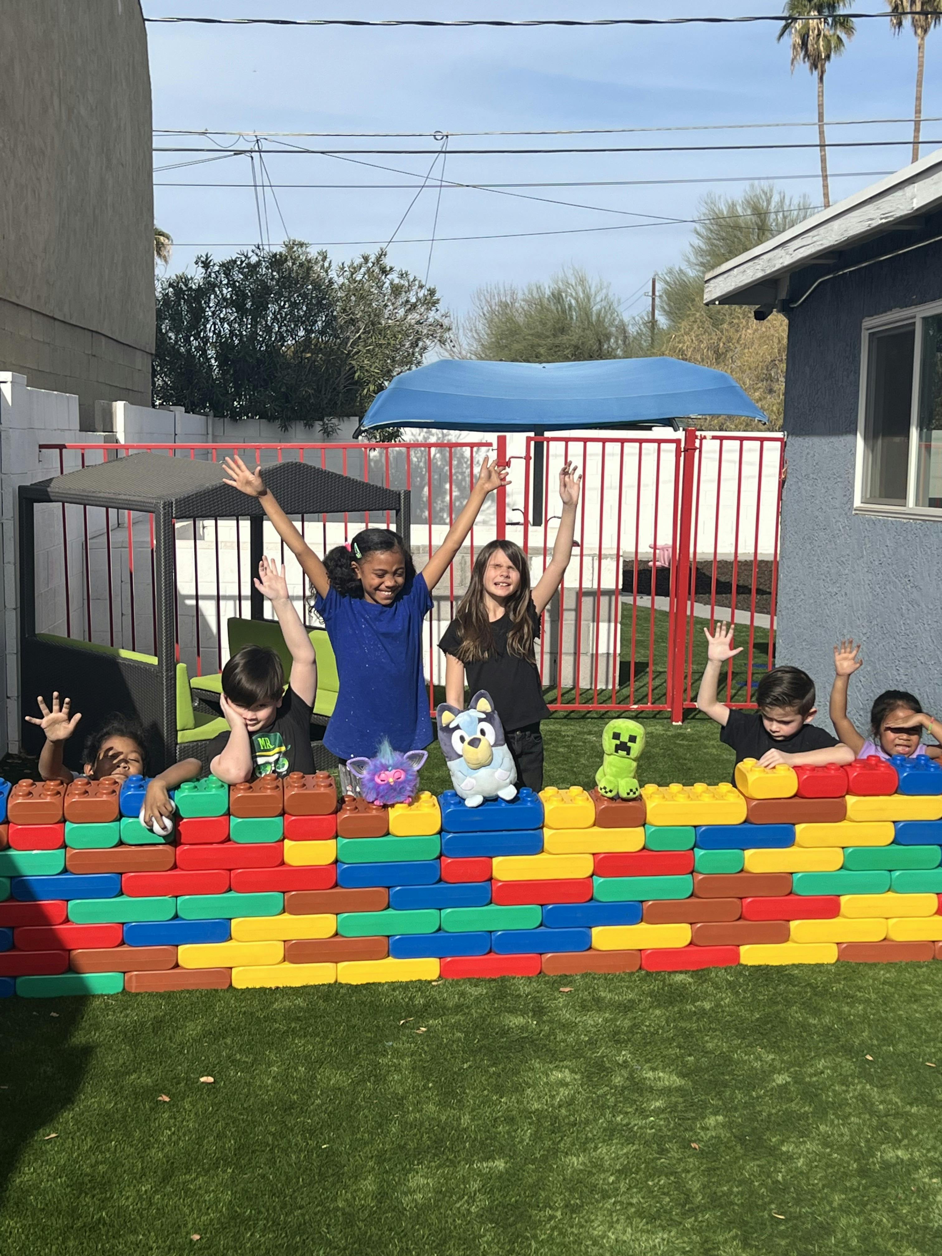 Children playing behind a colorful block wall outdoors