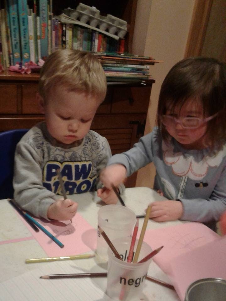 Two children drawing with colored pencils at a table