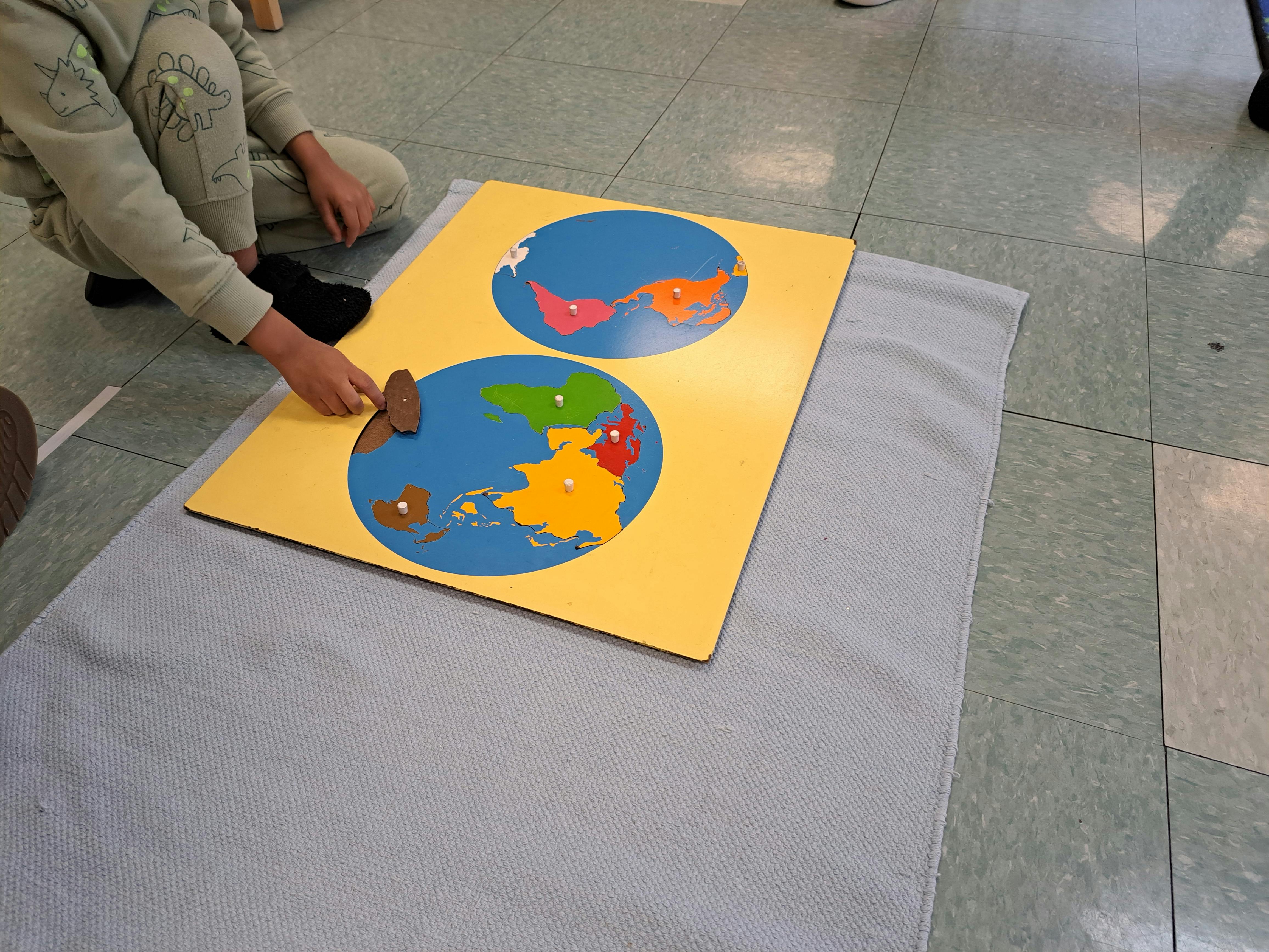 Child placing a puzzle piece into a world map puzzle