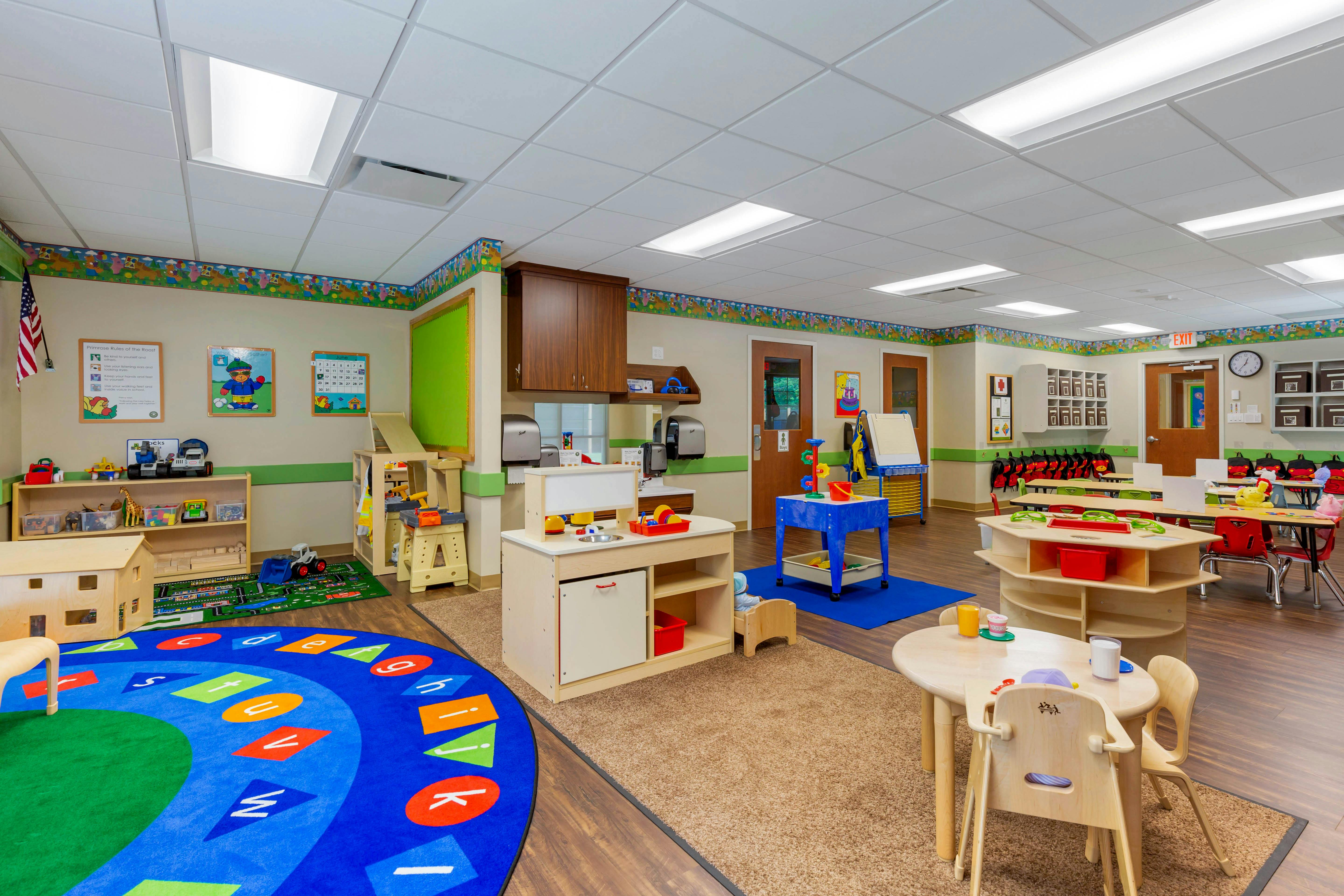 Colorful preschool classroom with various activity stations and small tables and chairs