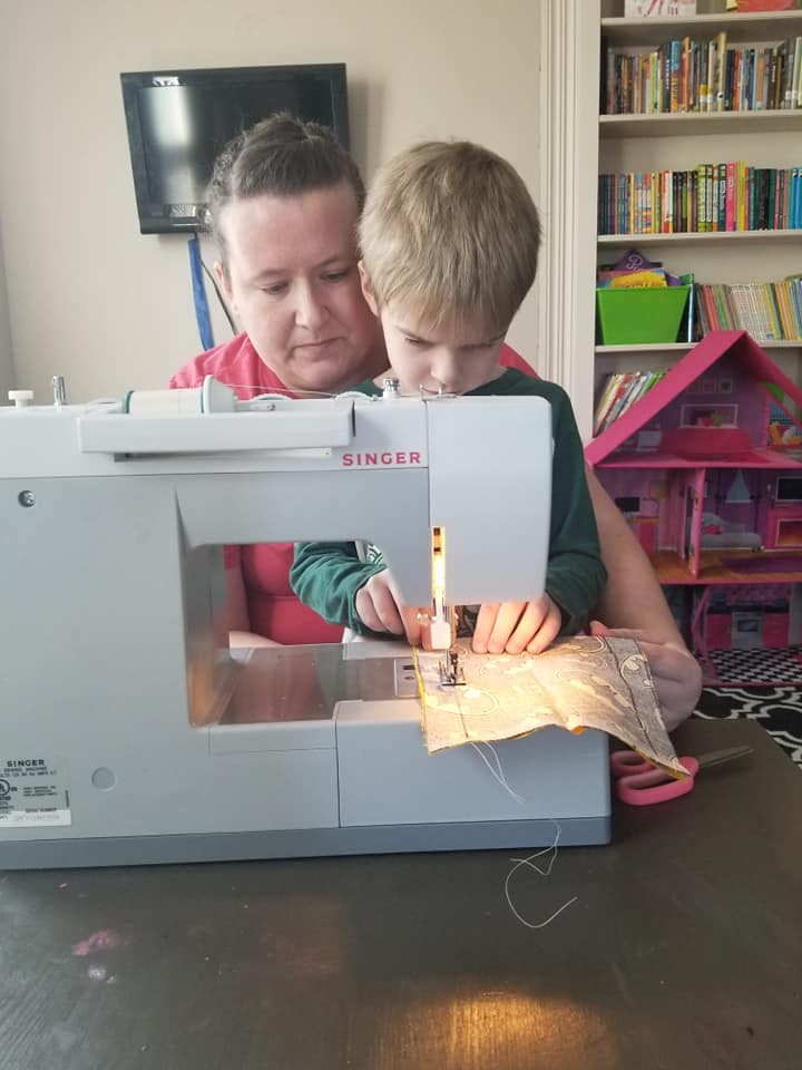 Person and child using a sewing machine
