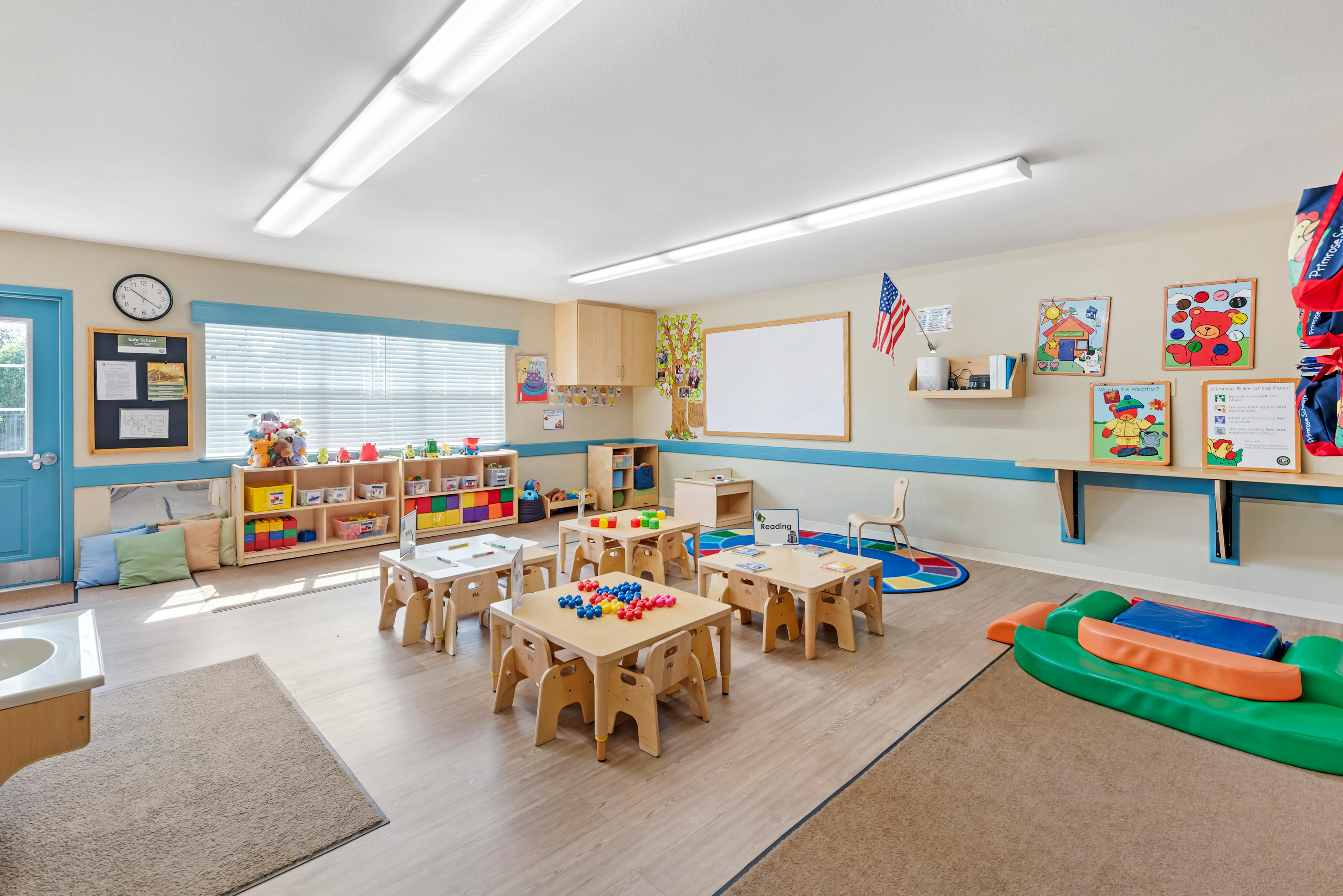 An empty early childhood classroom with small tables and chairs