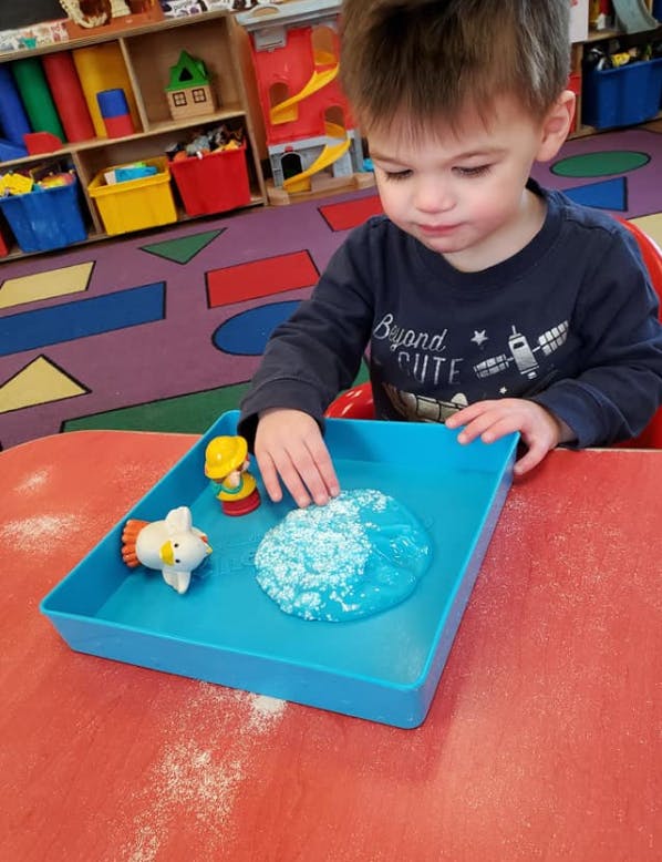 Child playing with slime in a blue tray