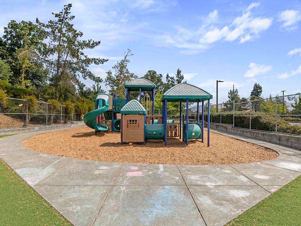 Playground with green and brown play structure on wood chips