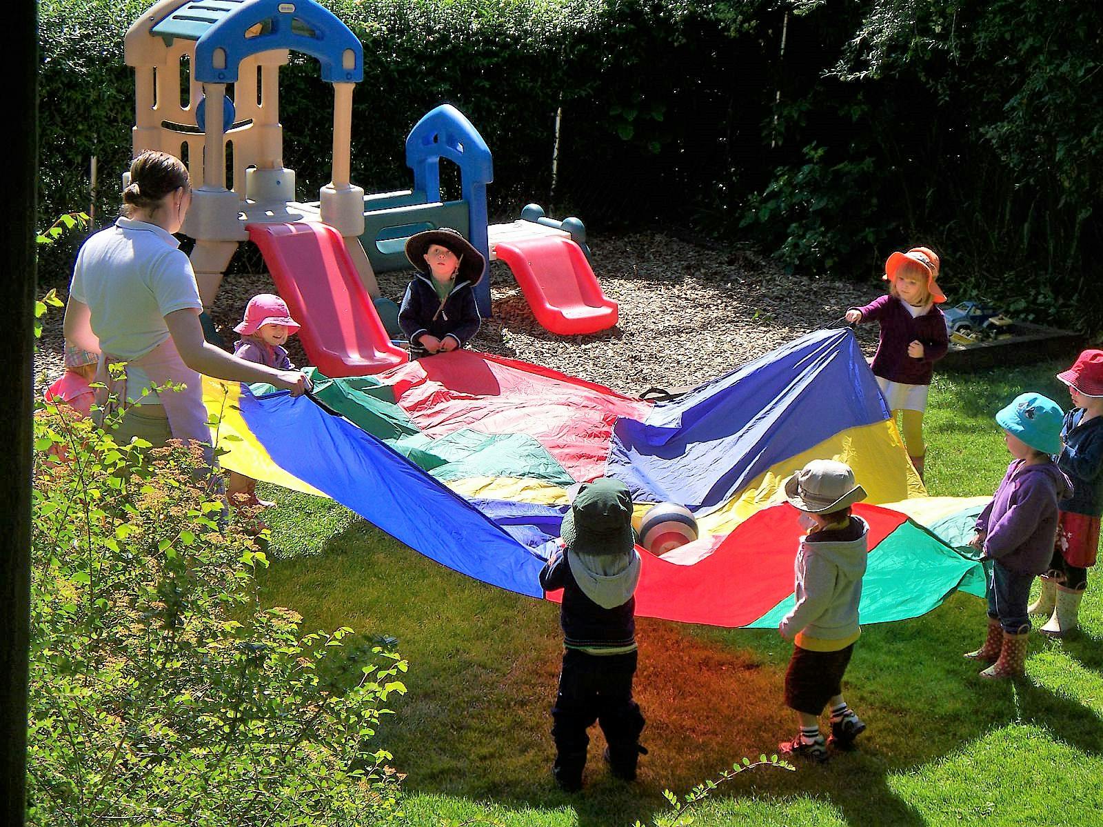 Person and children playing with a colorful parachute outdoors