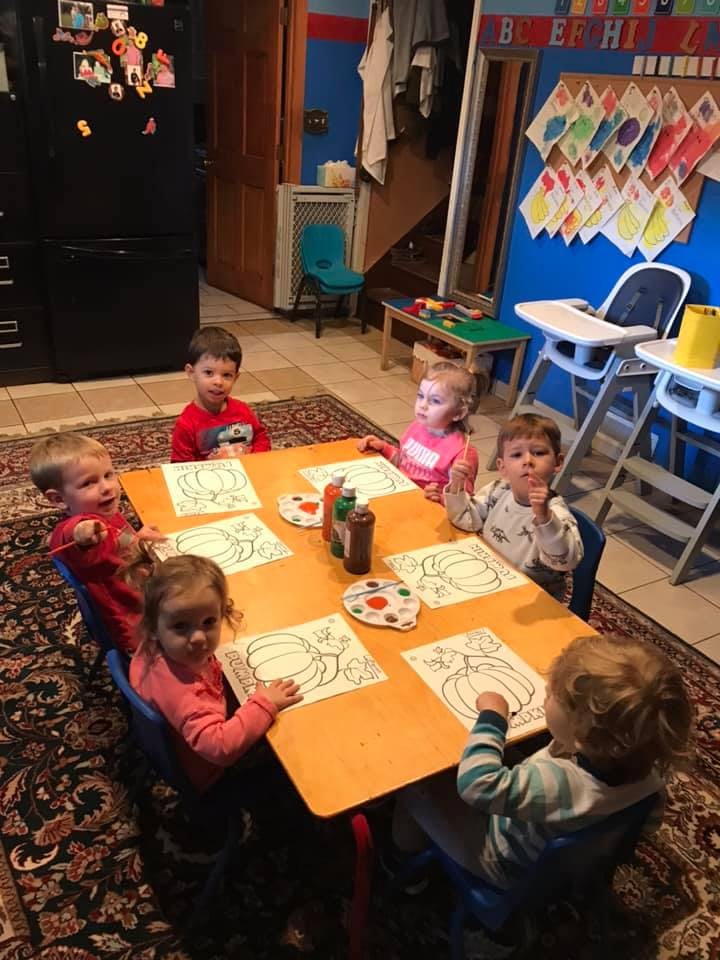 Children sitting at a table with pumpkin drawings and leaf drawings