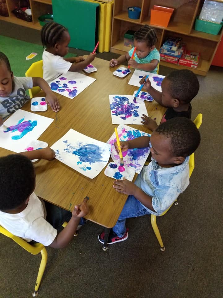 Children painting at a table in a classroom