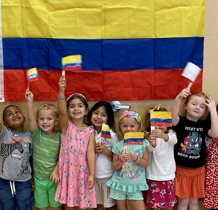 Children holding small flags in front of a large flag