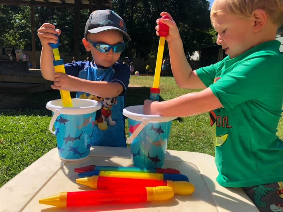 Two children playing with buckets and water toys