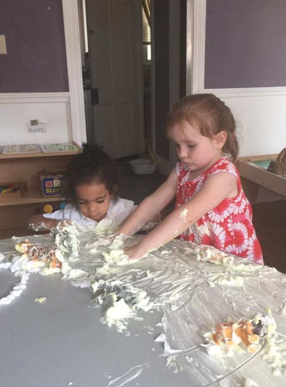 Two children playing with a messy substance on a table