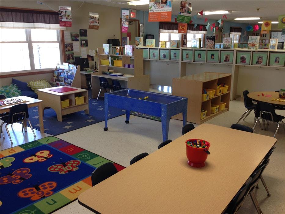 Classroom with child-sized tables, chairs, bookshelves, and a blue sensory table