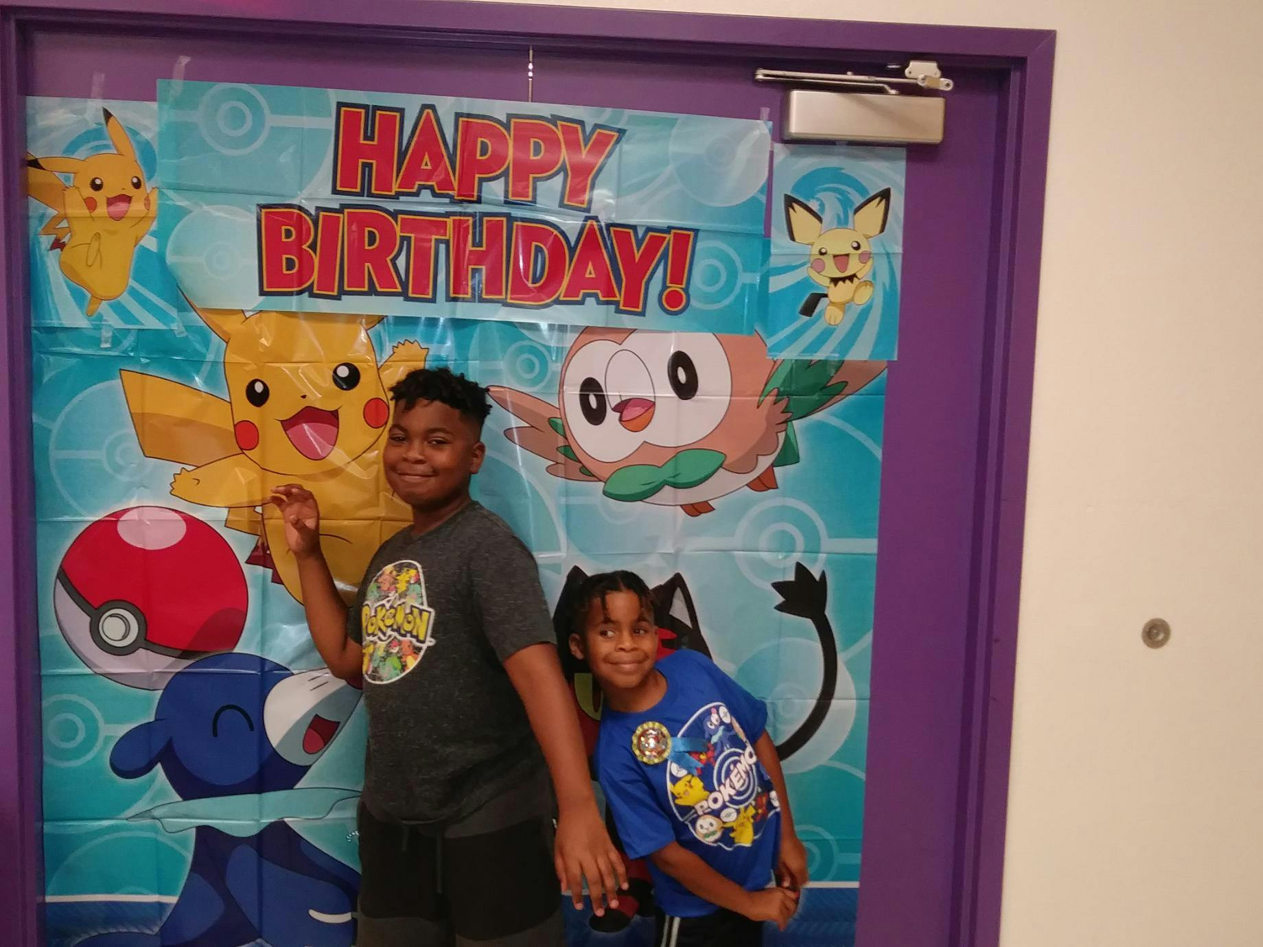 Two children standing in front of a Happy Birthday banner